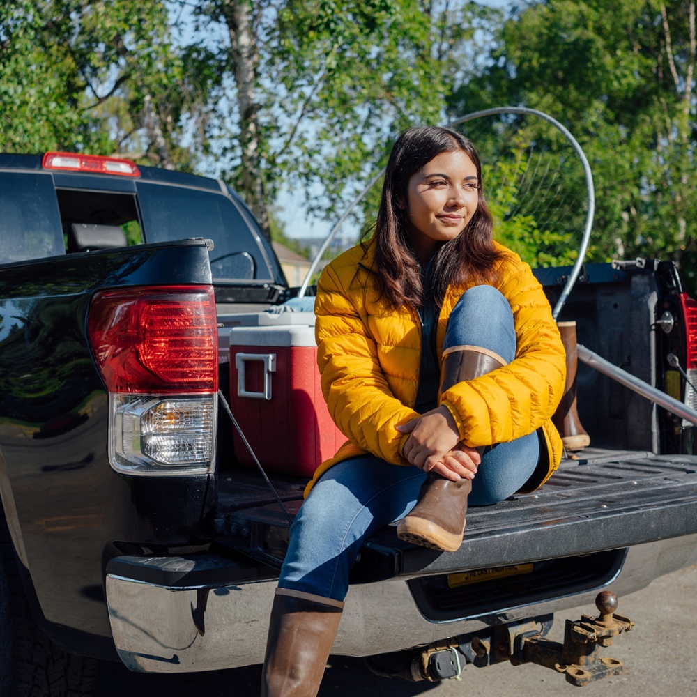 Woman sitting in the back of her truck with fishing gear