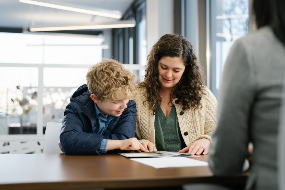 A woman and her child reviewing account options on paper at a desk