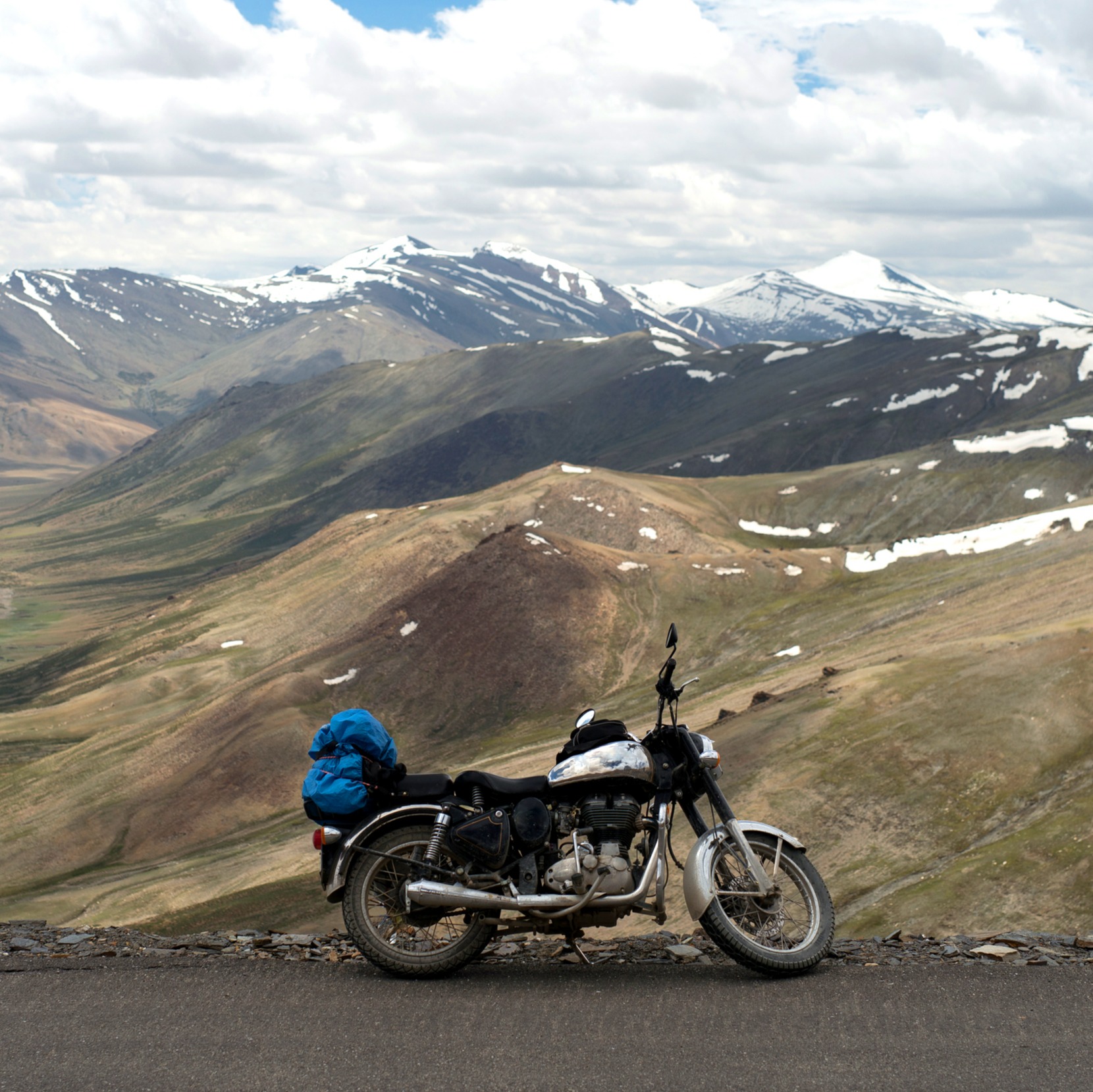 Motorcycle parked on side of road with mountains in the background