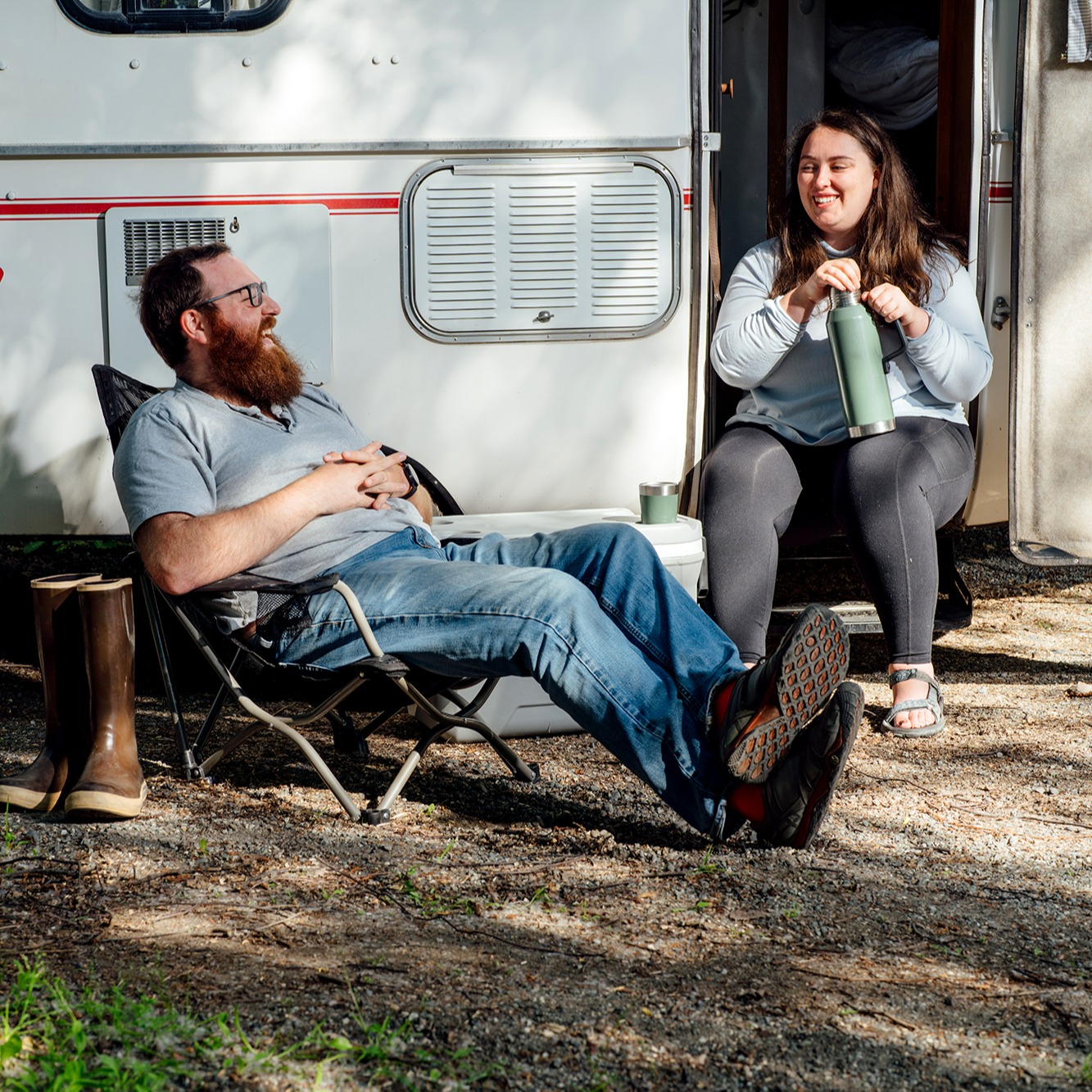 Two people sitting in front of their camper laughing