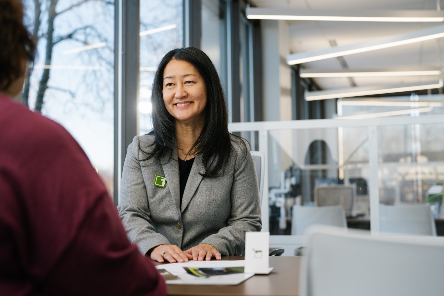 Professional woman in a suit sitting behind a desk with another person in the foreground